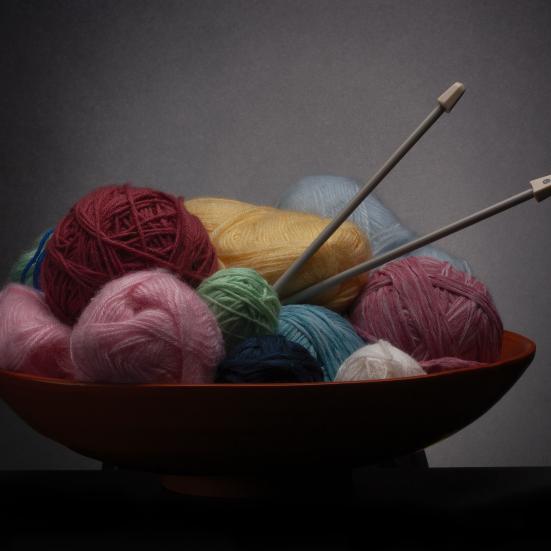 En skål med garnnøgler og strikkepinde.