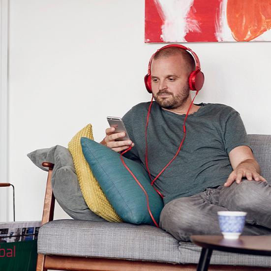 eReolen Global mand i sofa lyttende til en lydbog